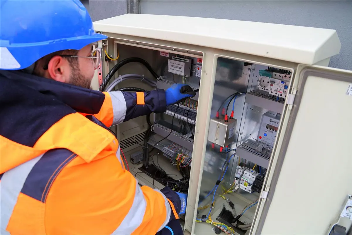 Eletricista inspecionando gabinete elétrico com instrumentos de medição