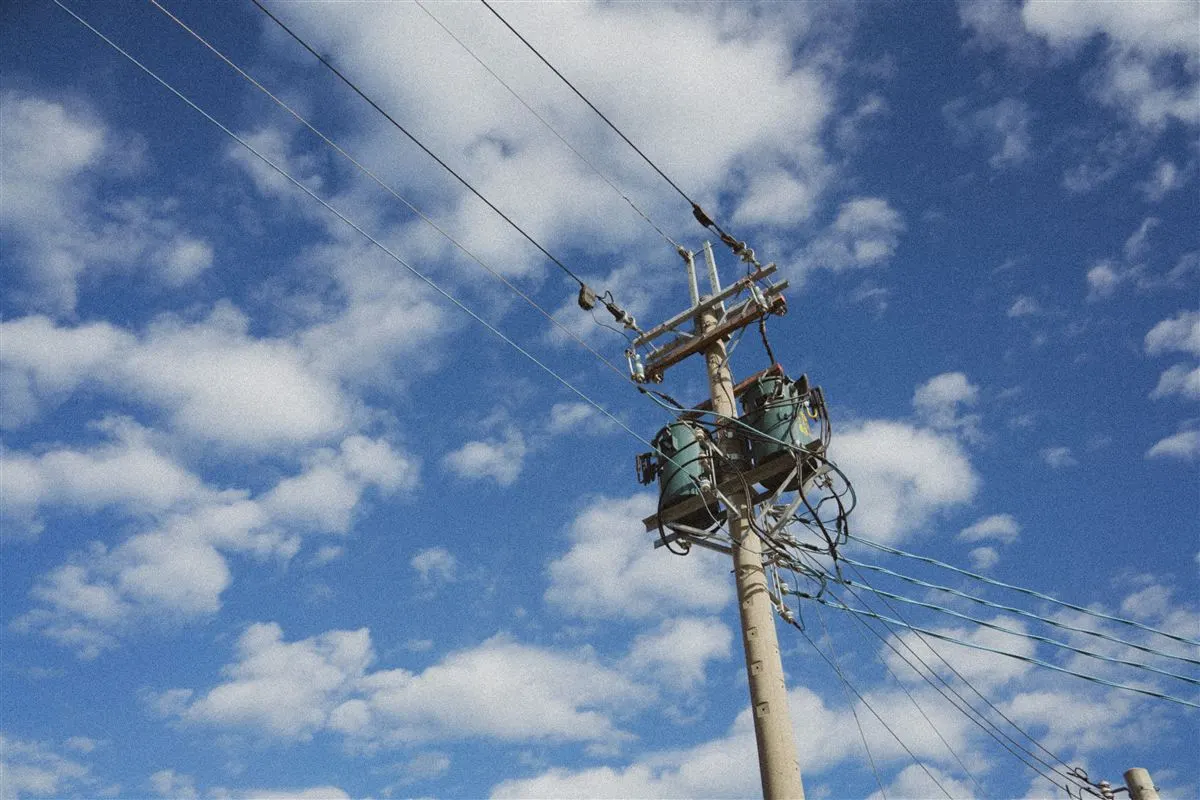 Poste de rede elétrica com transformadores contra céu azul